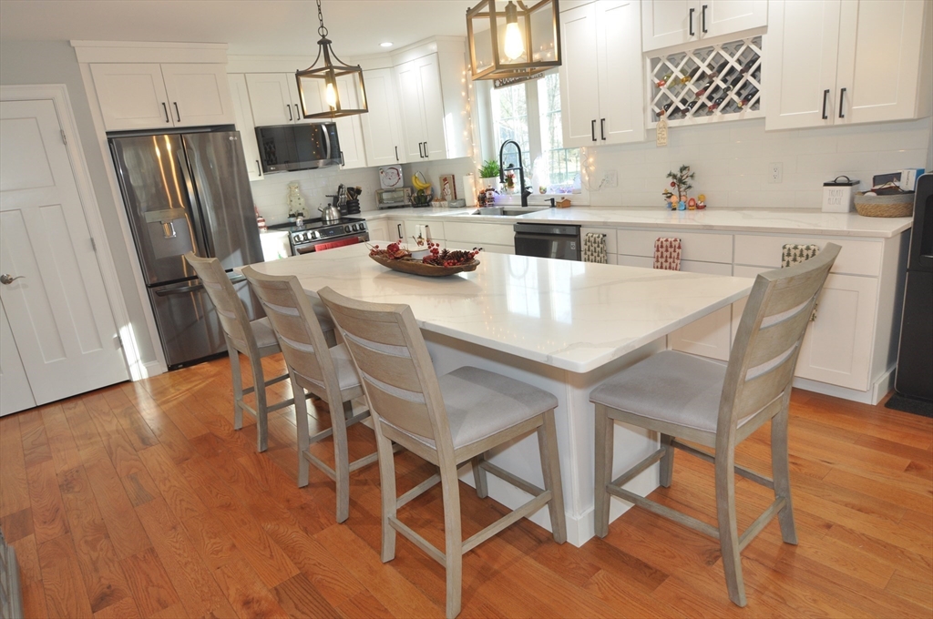 47 Maple Street, Unit A Middleton, MA 01949 - Photo 7 of 29 a kitchen with stainless steel appliances a dining table chairs refrigerator and sink