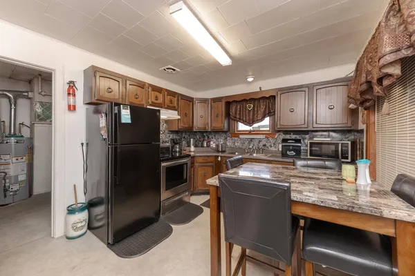 a kitchen with granite countertop a refrigerator and a stove top oven