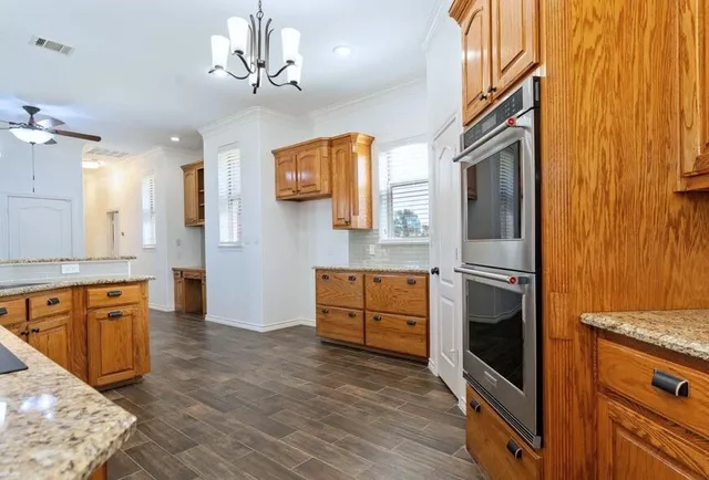 a kitchen with stainless steel appliances granite countertop a sink a stove and a wooden floor