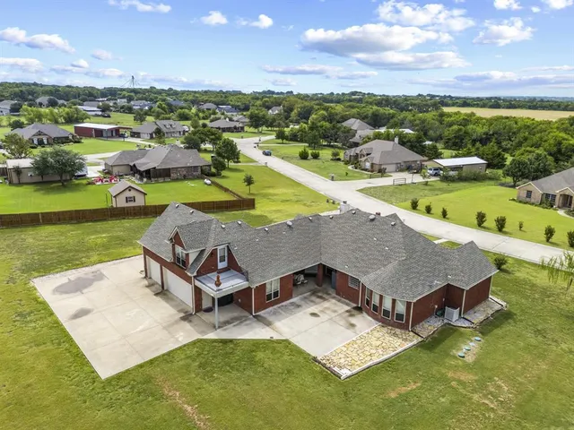 an aerial view of a house with swimming pool a yard and lake view