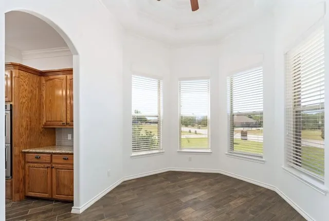 a view of an empty room with a window and a kitchen