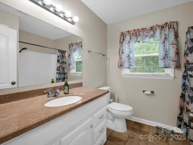 a bathroom with a granite countertop sink toilet and a mirror