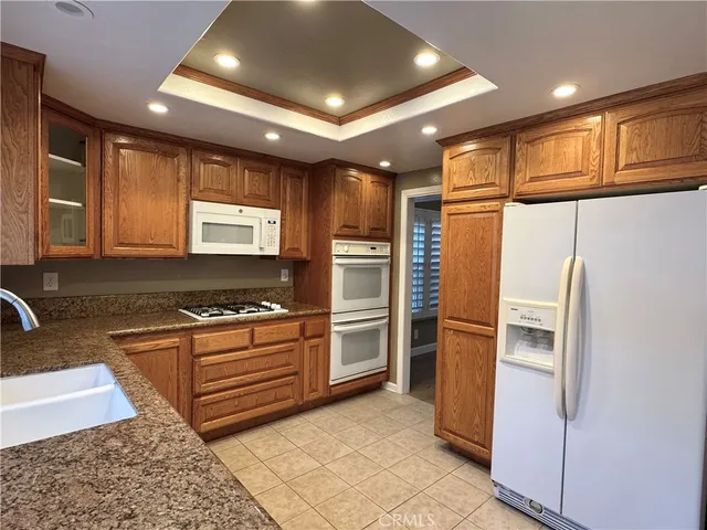 a kitchen with stainless steel appliances granite countertop a refrigerator a sink and a stove