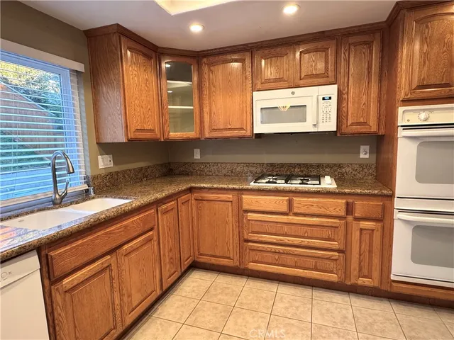 a kitchen with granite countertop stainless steel appliances a sink window and cabinets