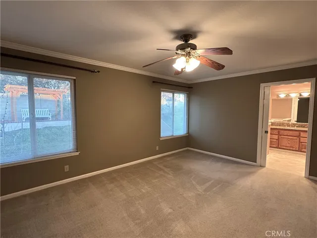 an empty room with chandelier fan and windows