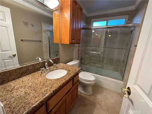 a bathroom with a granite countertop sink toilet mirror and shower