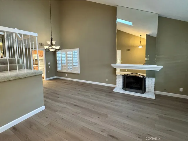 a view of an empty room with wooden floor and a fireplace