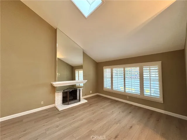 an empty room with wooden floor fireplace and windows
