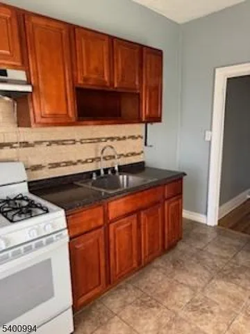 a kitchen with granite countertop a stove sink and cabinets