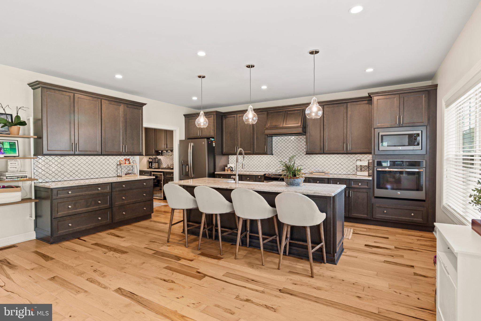 1413 Cortez Road Blue Bell, PA 19422 - Photo 15 of 66 a open kitchen with stainless steel appliances kitchen island granite countertop a refrigerator a stove a sink a dining table and chairs with wooden floor