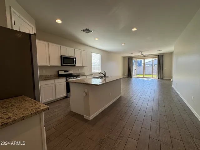 a kitchen with kitchen island granite countertop a stove top oven a sink and a refrigerator