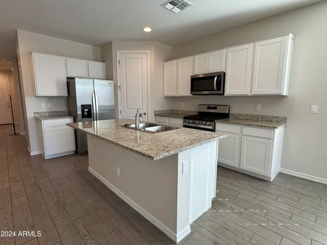 a kitchen with stainless steel appliances granite countertop a stove top oven a refrigerator a sink and dishwasher with wooden floor