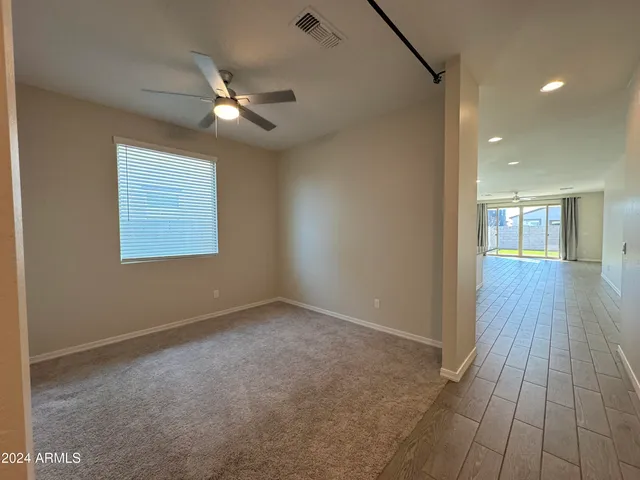 a view of an empty room with wooden floor and a ceiling fan