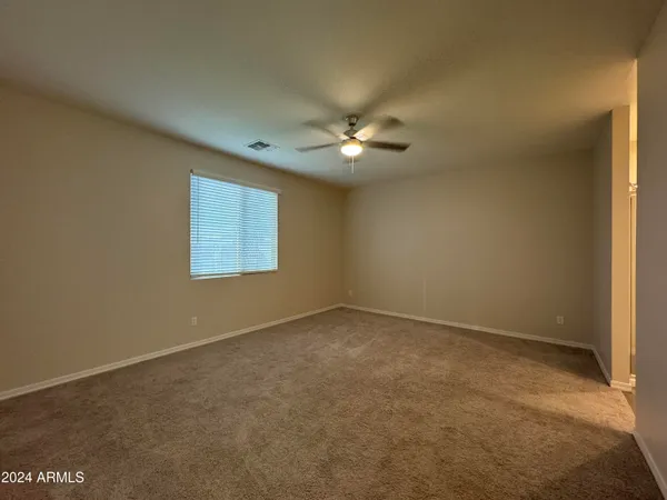 an empty room with a chandelier fan and windows