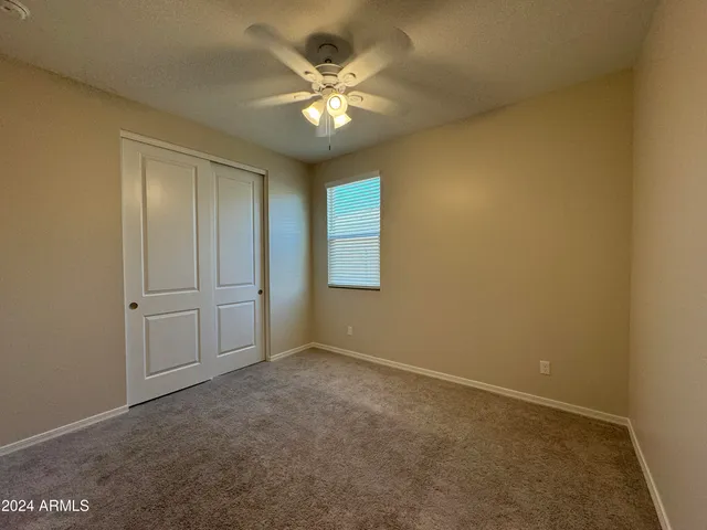 an empty room with a chandelier fan and windows