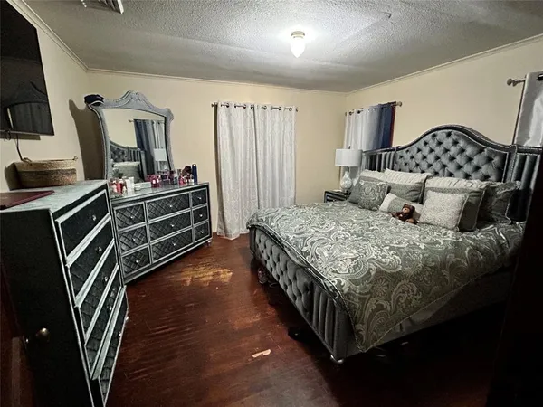 a bedroom with a bed a mirror on the dresser and a flat screen tv