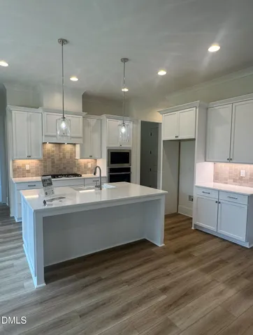 a large kitchen with kitchen island a sink dishwasher a refrigerator and a oven with wooden floor