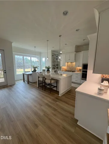 a living room with stainless steel appliances kitchen island granite countertop furniture and a wooden floor