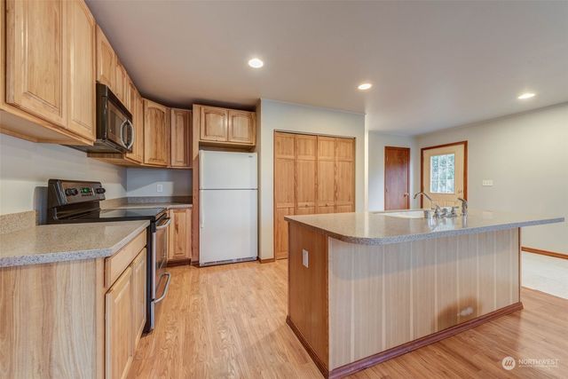 a kitchen with granite countertop a refrigerator a sink dishwasher a stove and white countertops with wooden floor