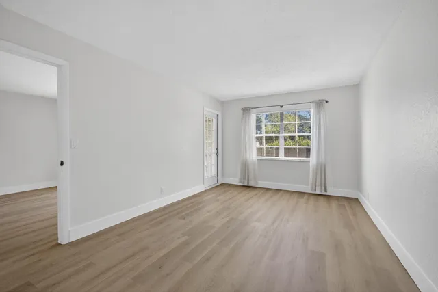 a view of an empty room with wooden floor and windows
