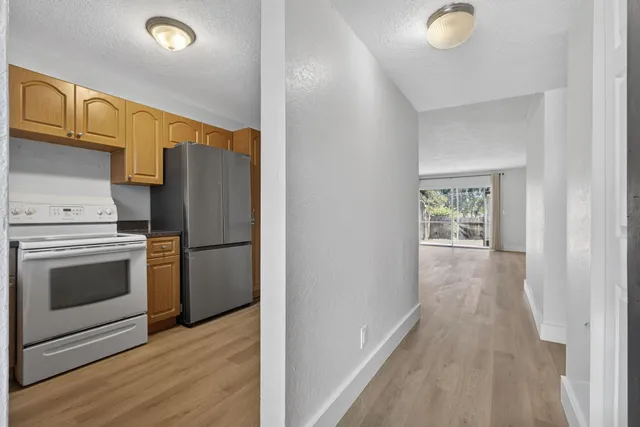 a view of a kitchen with a stove wooden cabinets and entryway
