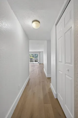 a view of a hallway with wooden floor and a bathroom