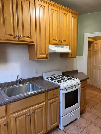 a kitchen with granite countertop a sink a stove and cabinets