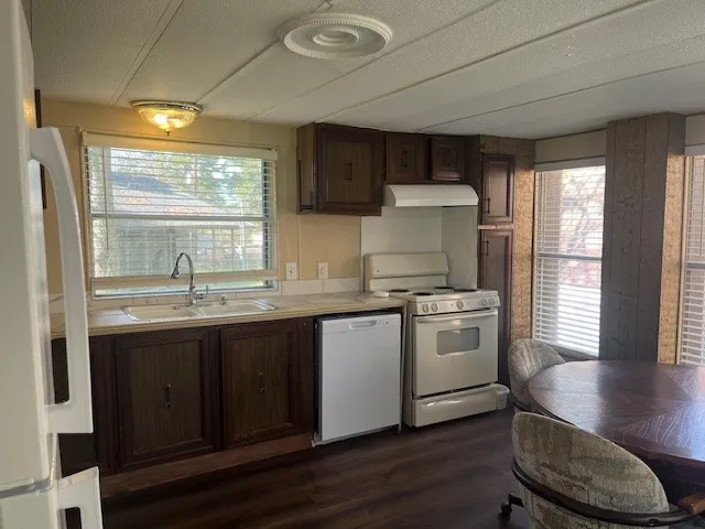 a kitchen with stainless steel appliances granite countertop a stove a sink dishwasher and a refrigerator with wooden floor