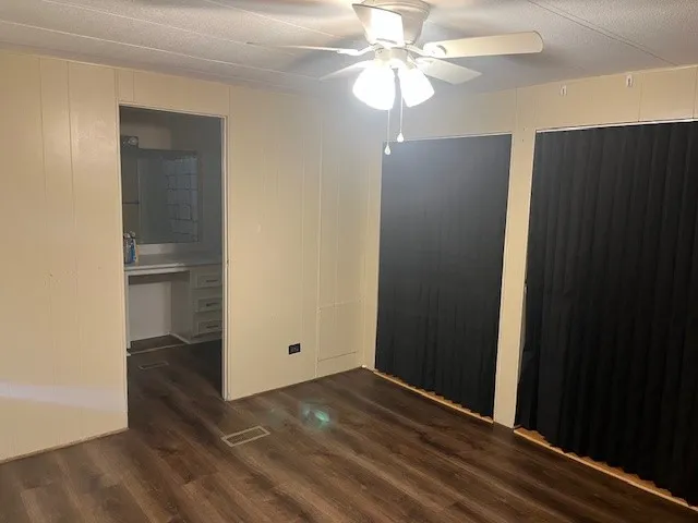 an empty room with wooden floor closet and windows