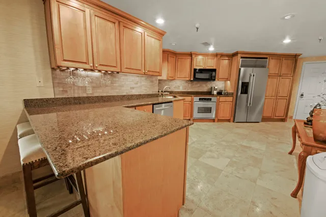 a kitchen with stainless steel appliances granite countertop a stove top oven a sink a refrigerator white cabinets and granite countertops