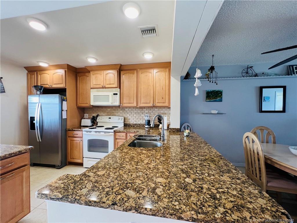 7430 South Ocean Drive, Unit 619B Jensen Beach, FL 34957 - Photo 5 of 57 a kitchen with granite countertop a refrigerator stove top oven and sink