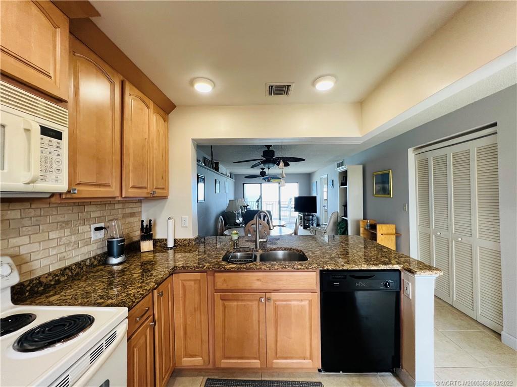 7430 South Ocean Drive, Unit 619B Jensen Beach, FL 34957 - Photo 9 of 57 a kitchen with granite countertop a sink stove and cabinets