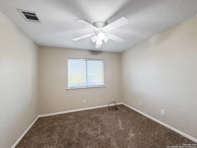 an empty room with a chandelier fan and windows