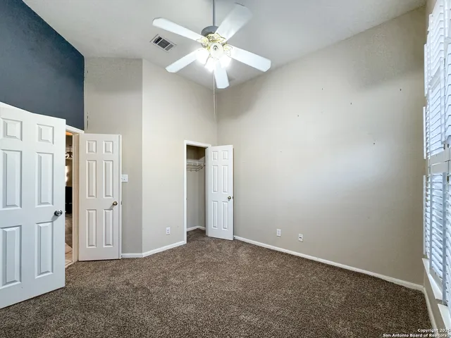 an empty room with windows and ceiling fan