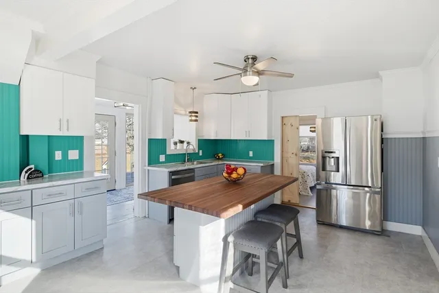 a kitchen with stainless steel appliances a refrigerator a sink a stove and white cabinets