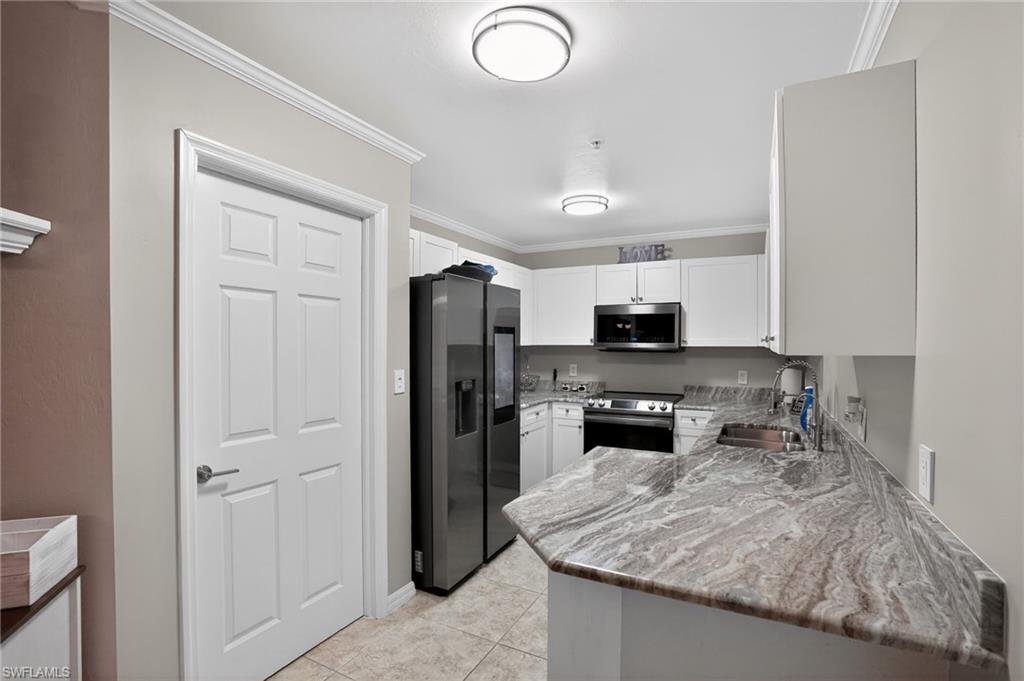 519 Roma Court, Unit 3101 Naples, FL 34110 - Photo 12 of 30 a kitchen with stainless steel appliances granite countertop a refrigerator stove and sink