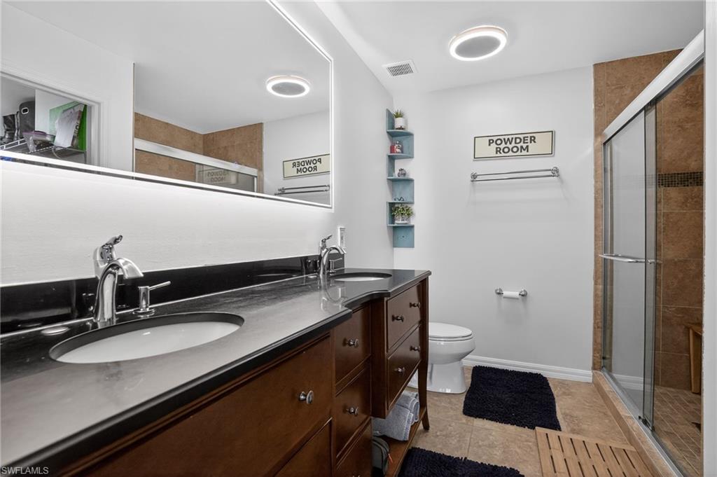 519 Roma Court, Unit 3101 Naples, FL 34110 - Photo 24 of 30 a bathroom with a sink a toilet a mirror and shower