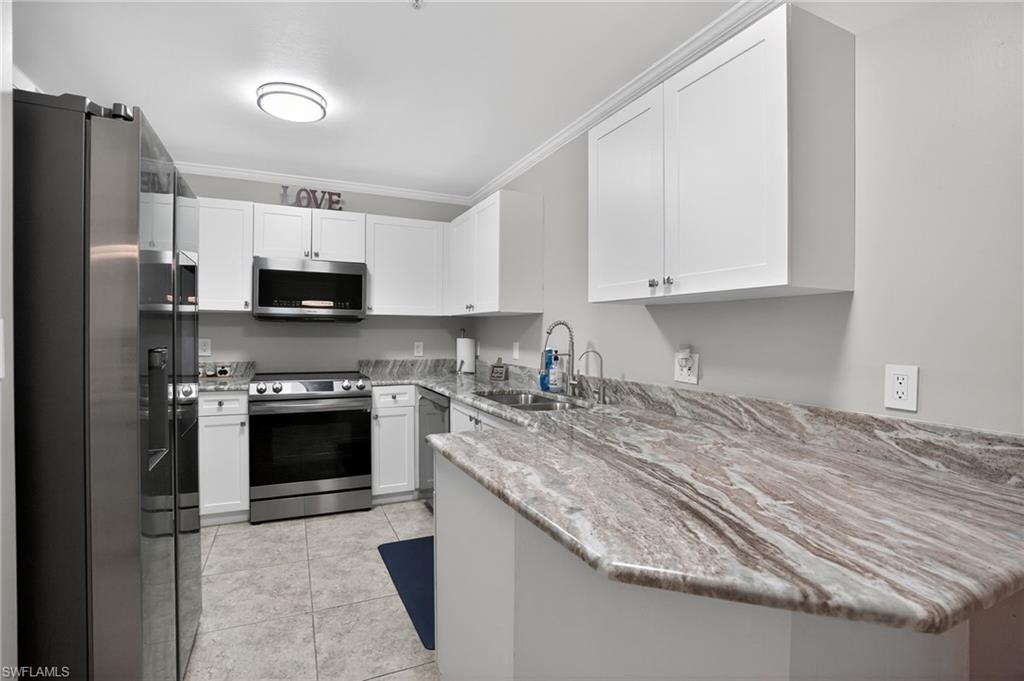 519 Roma Court, Unit 3101 Naples, FL 34110 - Photo 9 of 30 a kitchen with stainless steel appliances granite countertop a stove top oven a sink and a refrigerator