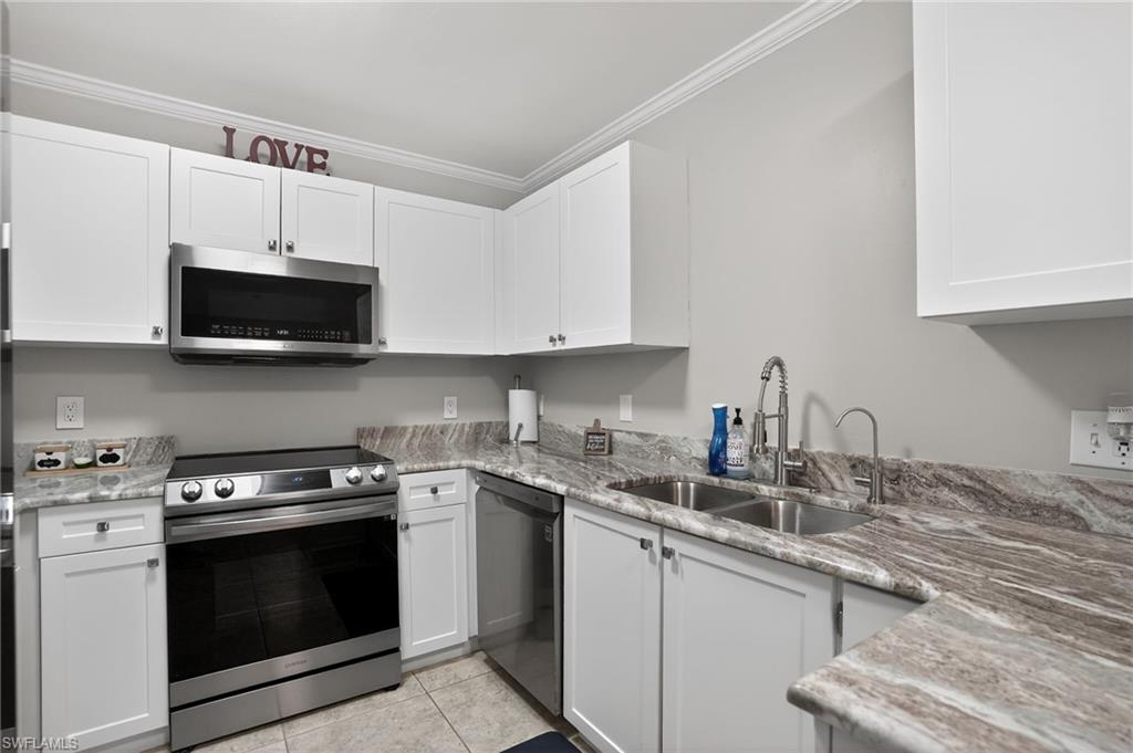 519 Roma Court, Unit 3101 Naples, FL 34110 - Photo 10 of 30 a kitchen with stainless steel appliances granite countertop a sink a stove a microwave and cabinets