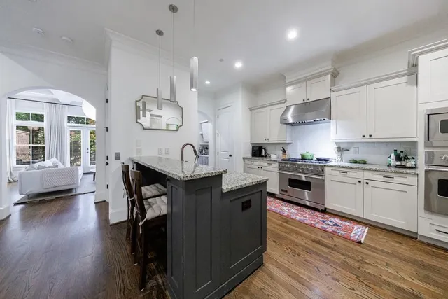 a kitchen with stainless steel appliances granite countertop a stove and white cabinets