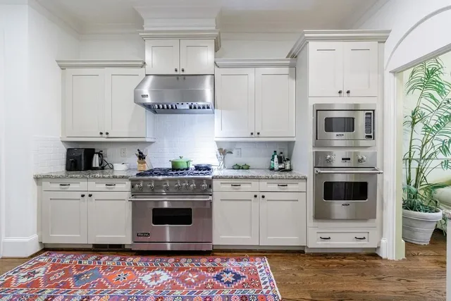 a large kitchen with stainless steel appliances a stove a sink dishwasher a refrigerator and wooden floor