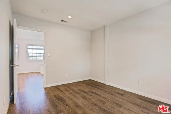 an empty room with wooden floor cabinet and windows