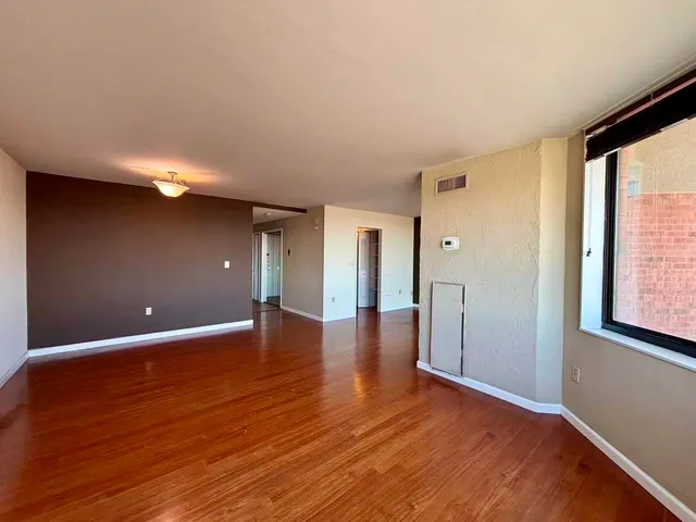a view of an empty room with wooden floor and a window