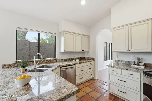 a kitchen with stainless steel appliances granite countertop a stove a sink and a granite counter tops with white cabinets