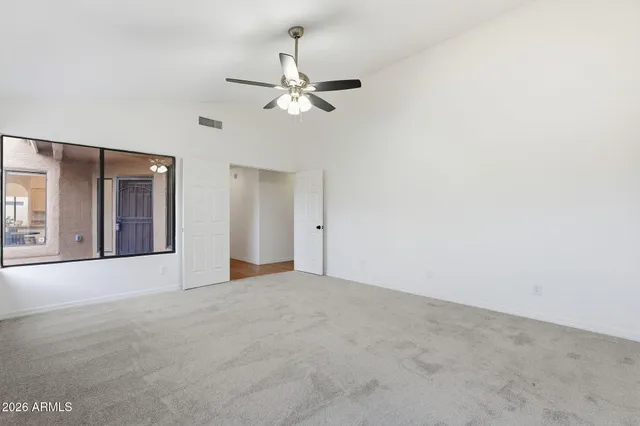 a view of an empty room with chandelier fan