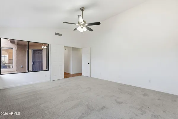 an empty room with chandelier fan and windows