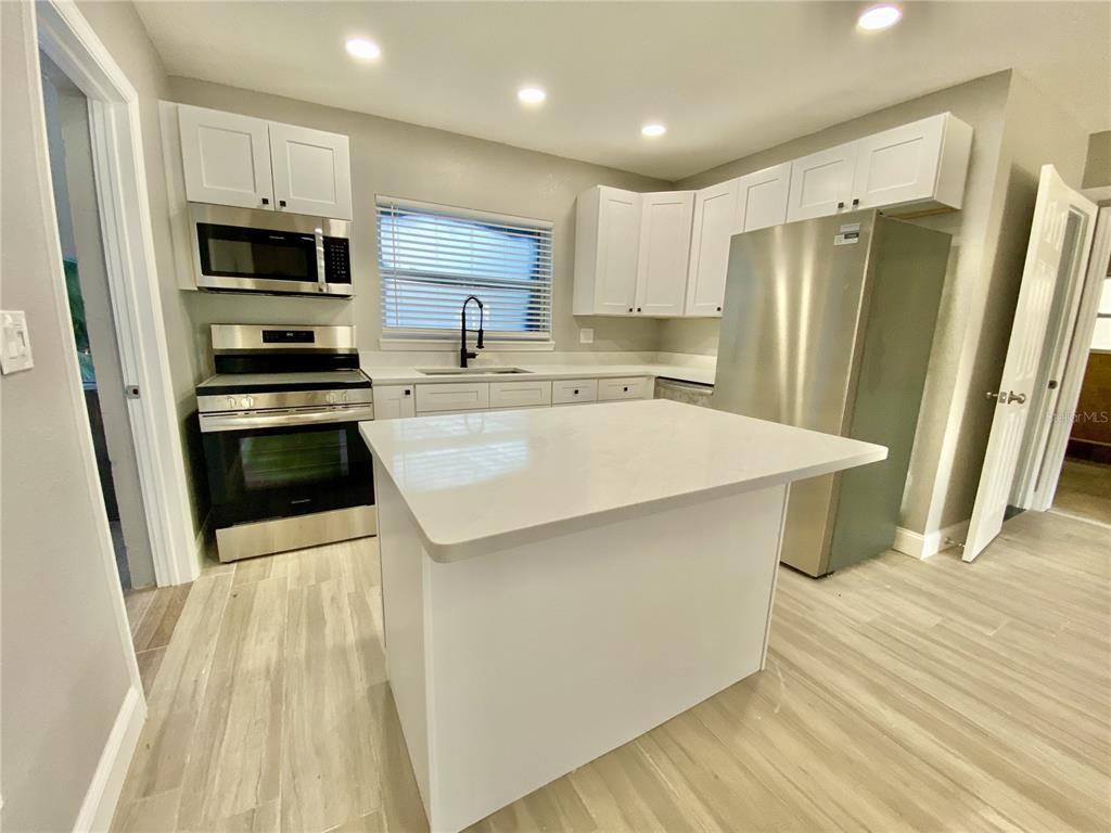 120 Grace Street Crystal Beach, FL 34681 - Photo 4 of 12 a kitchen with stainless steel appliances a refrigerator a stove a microwave and cabinets