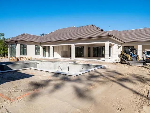a view of a white house with a large windows and a yard with palm trees