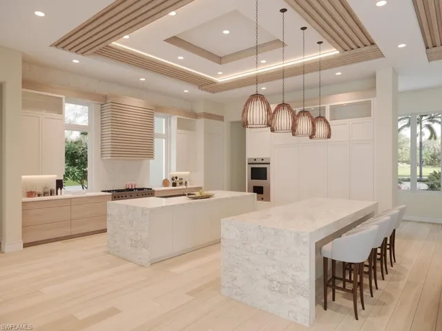 a large white kitchen with a large window a counter space and stainless steel appliances