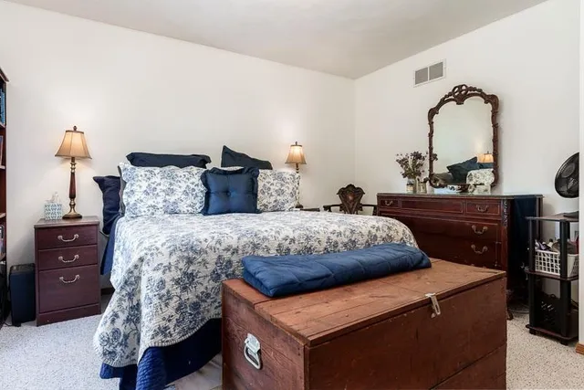 a bedroom with a bed and a dresser next to a window